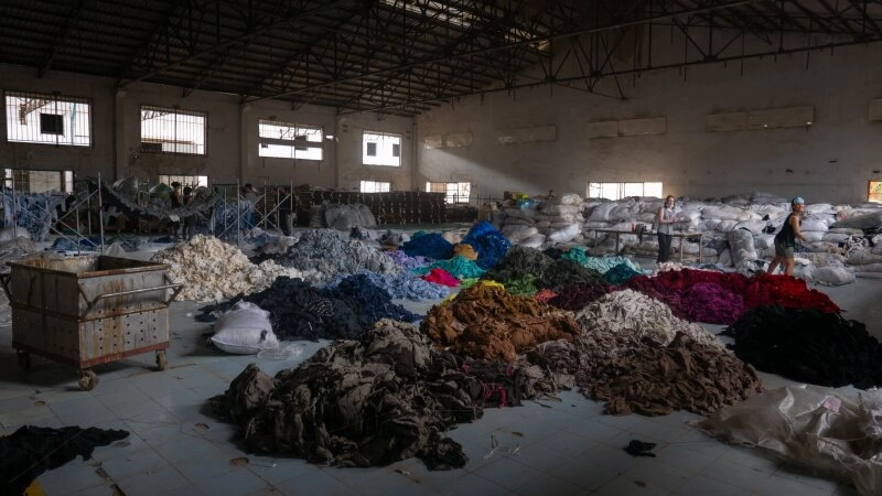 Berge von alten Kleidungsstücken in einer stillgelegten Fabrik.