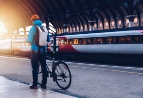 Mann mit Fahrrad am Bahnhof