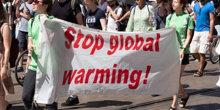 Protestanten halten ein Tuch mit der Aufschrift “Stop global warming!”.